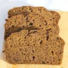 Three slices of pumpkin spice bread fanned on a wooden board.