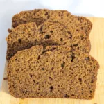 Three slices of pumpkin spice bread fanned on a wooden board.