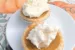 Two mini pumpkin pies with whipped cream topping on a white plate set on a fall pumpkin tablecloth.